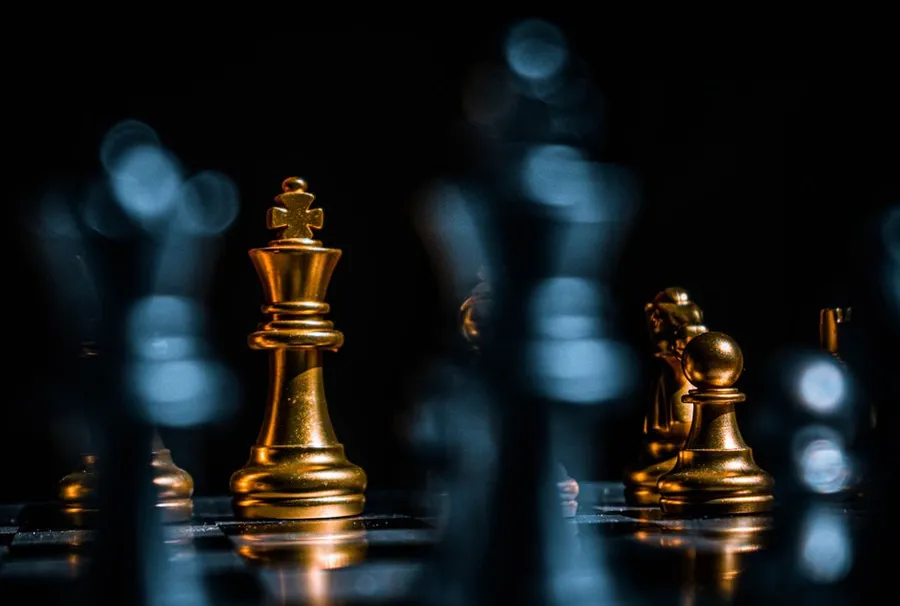 Golden chess pieces on a board in low light
