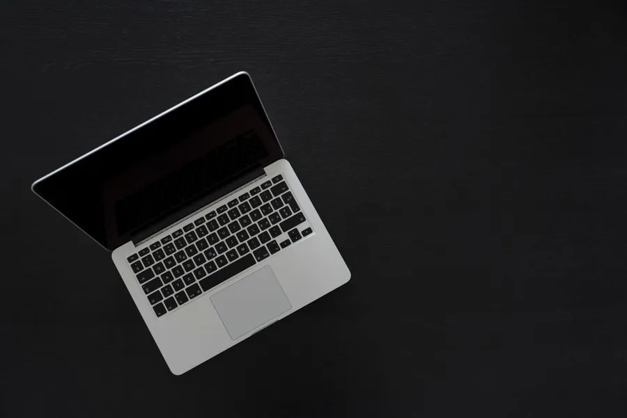 A minimalist laptop seen from above on a dark desk